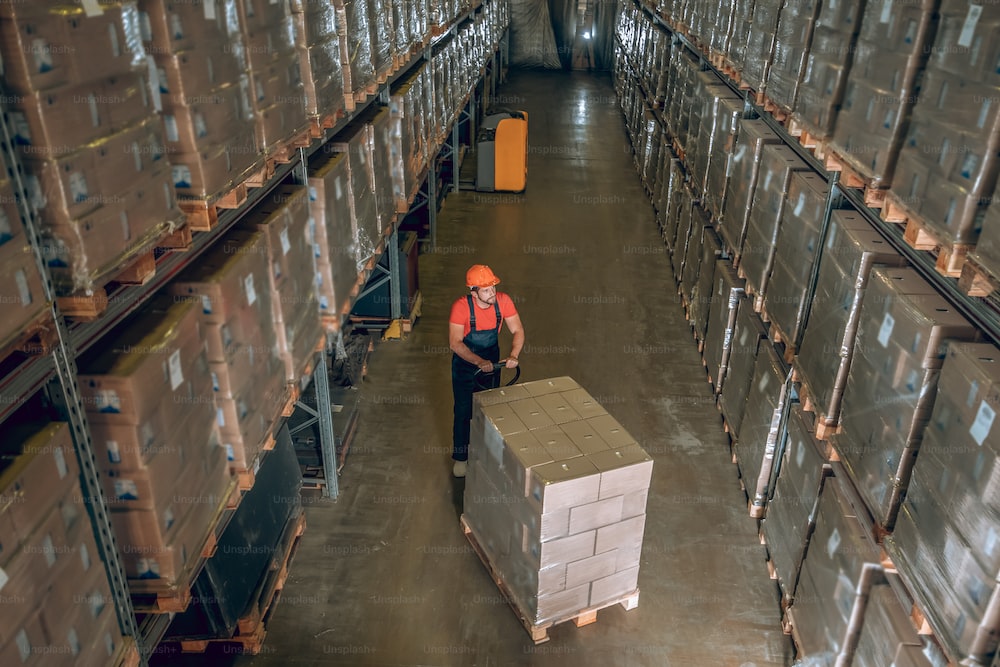 Work in warehouse. View of a person in megastore with lots of containers on the shelves